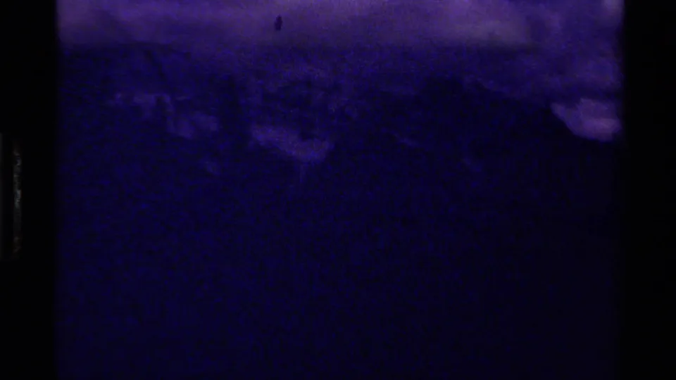 1979 Canadian 8mm frame showing a dim mountain landscape with heavy blue-purple cast and low-light exposure.