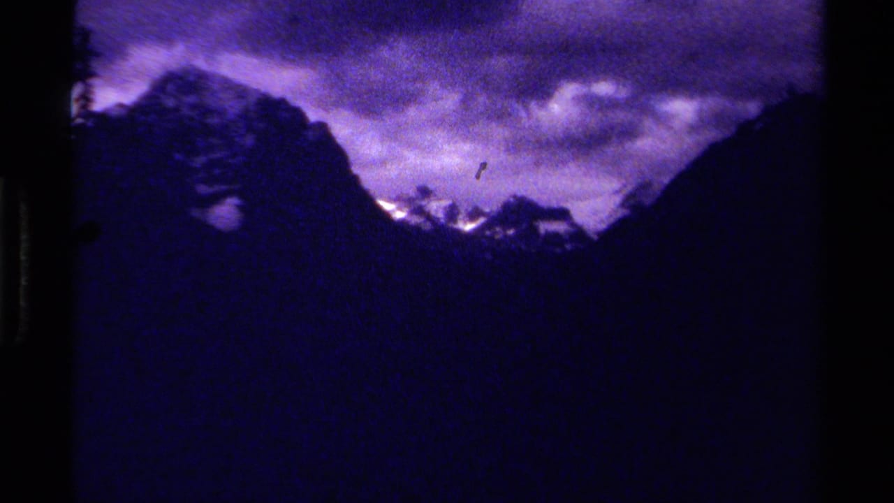 1979 8mm Canada footage showing dark mountain silhouettes, snow on distant peaks, and a purple cloudy sky.
