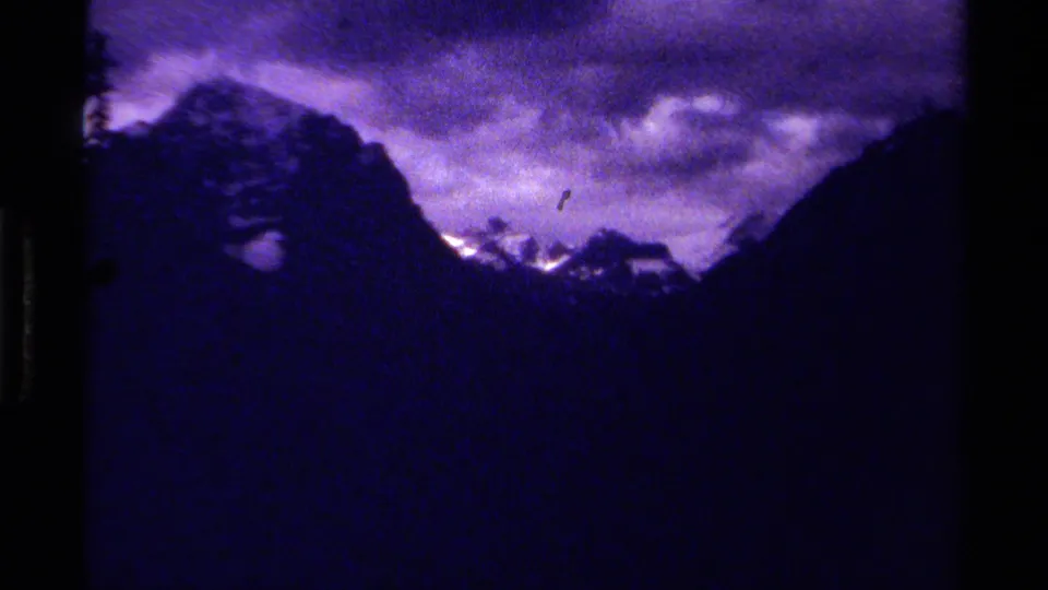 1979 8mm Canada footage showing dark mountain silhouettes, snow on distant peaks, and a purple cloudy sky.