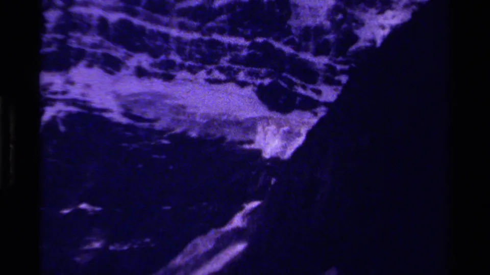 Purple-toned 8mm view of rugged Canadian Rockies terrain with shadowed ridges and grainy film texture.