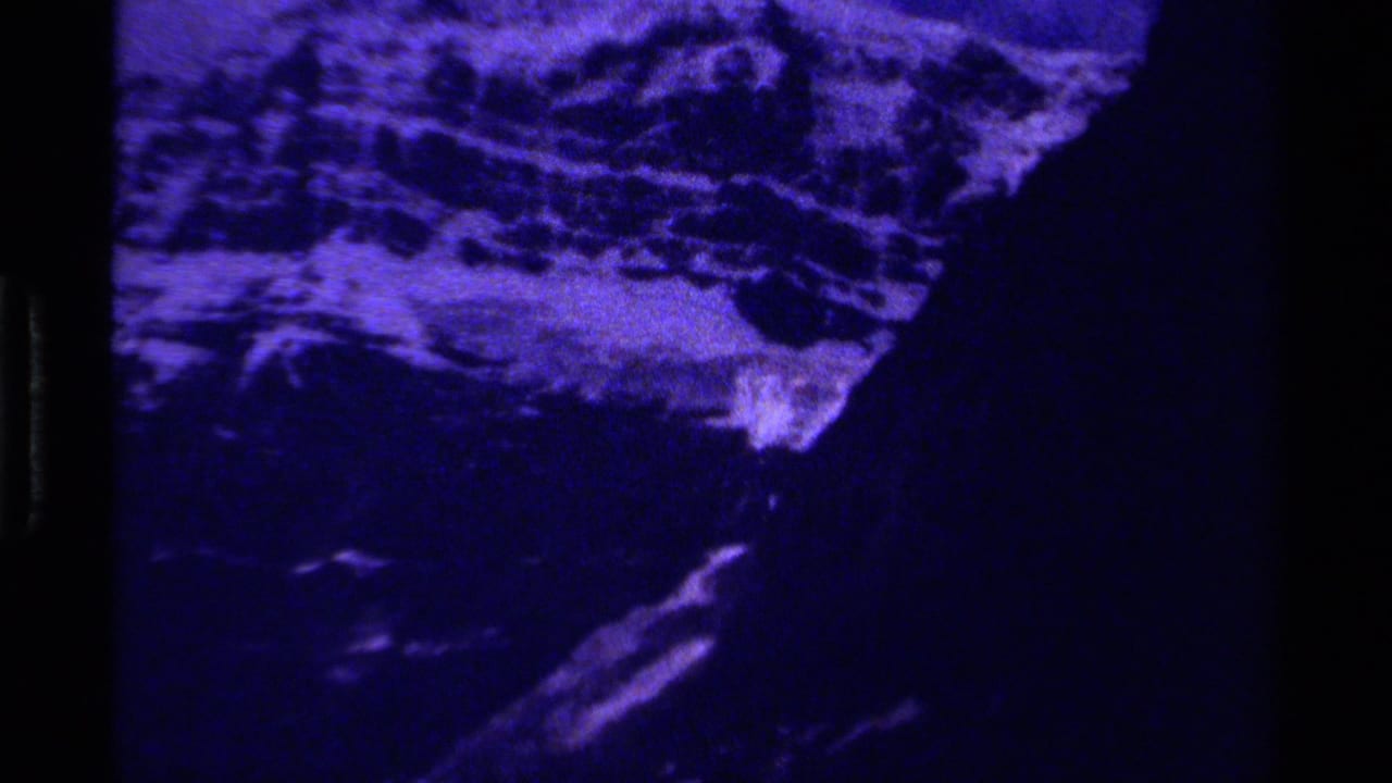 1979 Canada 8mm frame showing a heavily blue-toned view of snowy mountain terrain and dark rocky slopes.