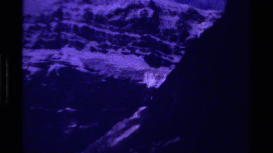1979 Canada 8mm frame showing a heavily blue-toned view of snowy mountain terrain and dark rocky slopes.