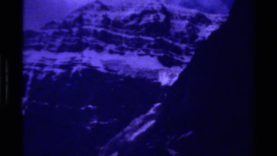 Heavily blue 1979 Canada 8mm frame showing snow-streaked mountains and shadowed valley terrain.