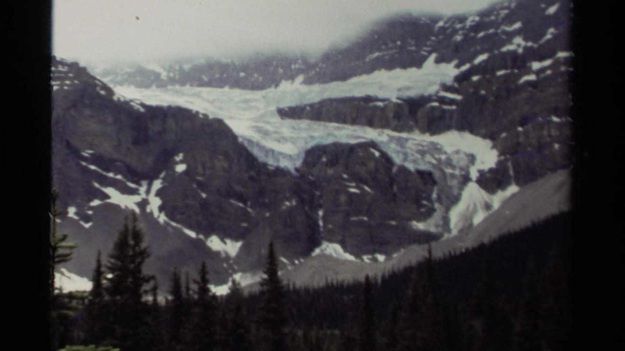 1979 Canada 8mm view of a glacier or snowfield set between rugged mountain slopes, with evergreen forest in the foreground.