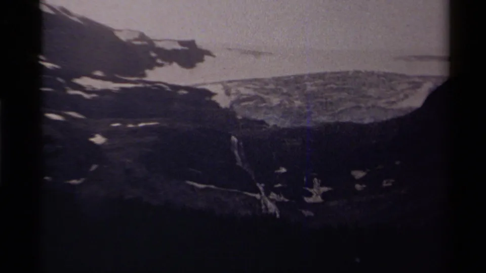 Final 1979 Canada 8mm frame with dim exposure over a snow-covered mountain slope and dark evergreen foreground.