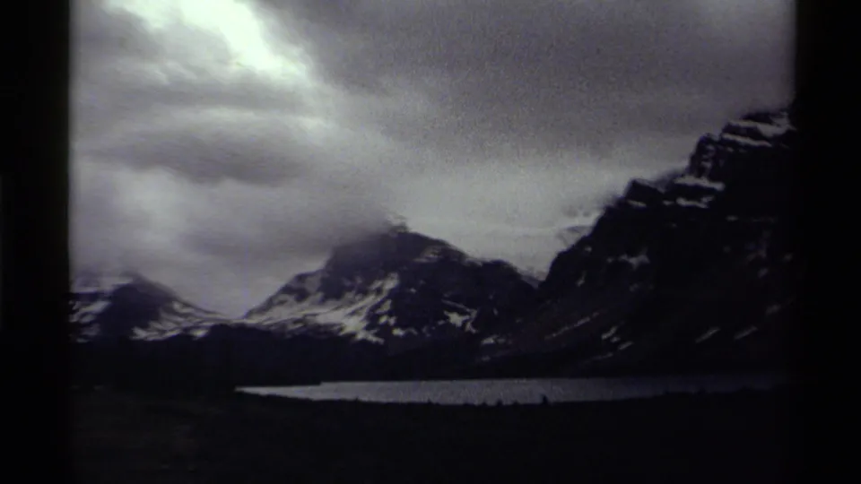 Canadian mountain lake landscape on 8mm film, with snowy ridges and low clouds across the peaks.