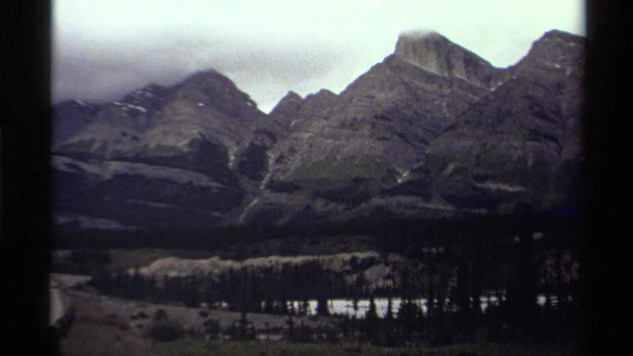 Mountain valley with ridges, trees, and reflective water below.