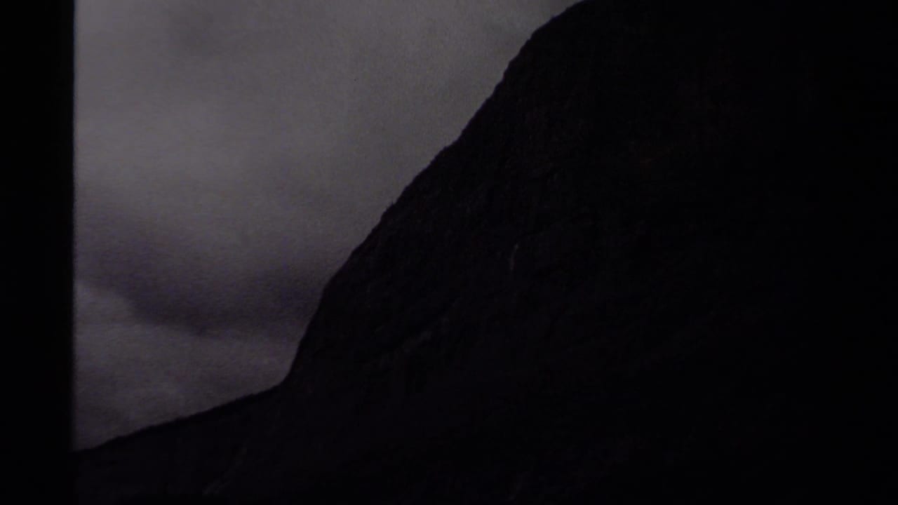 Canadian mountain landscape on 8mm film, with a steep shadowed rock face rising into an overcast sky.