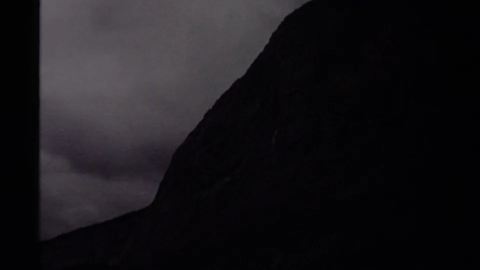 Canadian mountain landscape on 8mm film, with a steep shadowed rock face rising into an overcast sky.