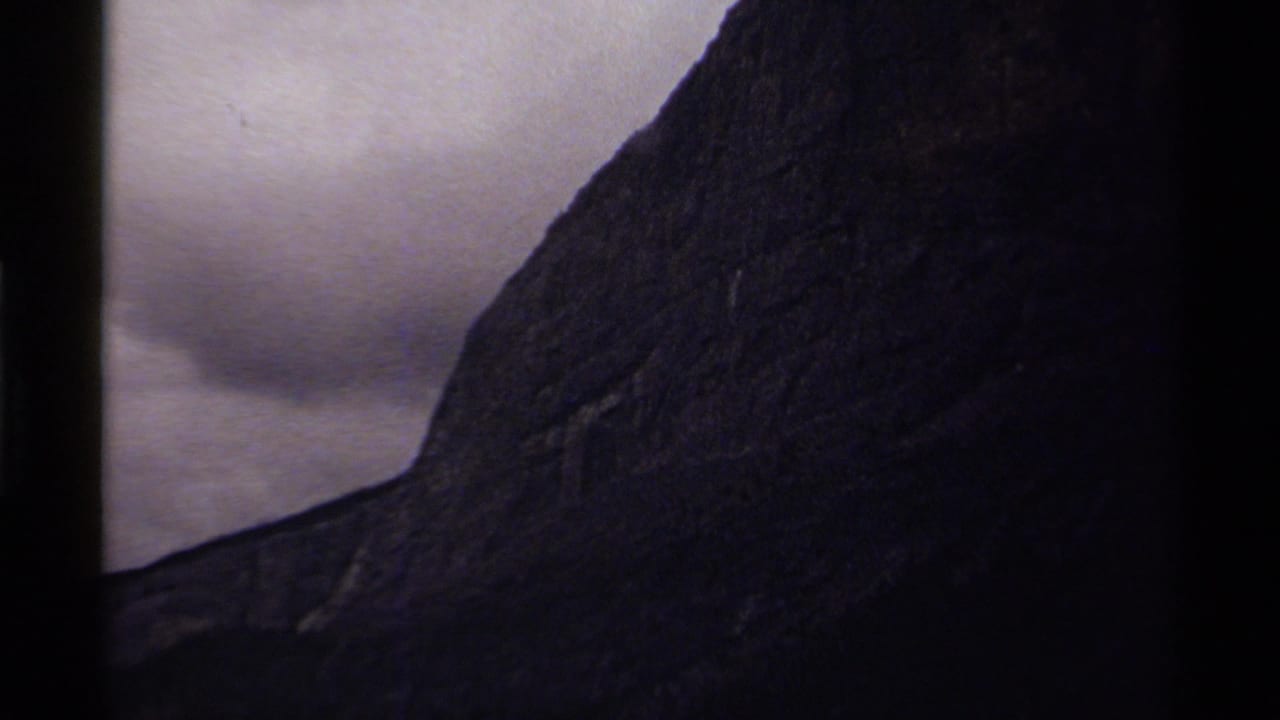 1979 Canada 8mm frame showing a steep dark mountain slope under an overcast sky, with visible film gate edges.