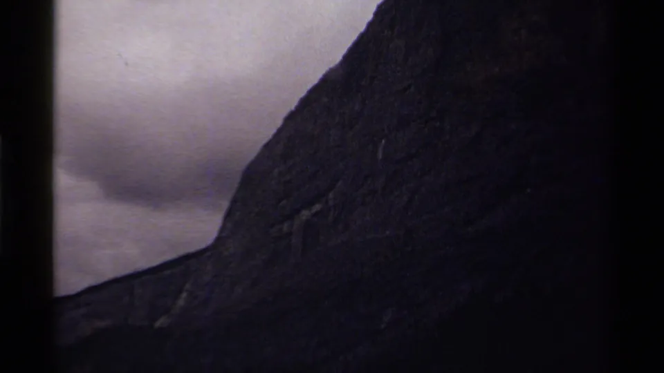 1979 Canada 8mm frame showing a steep dark mountain slope under an overcast sky, with visible film gate edges.