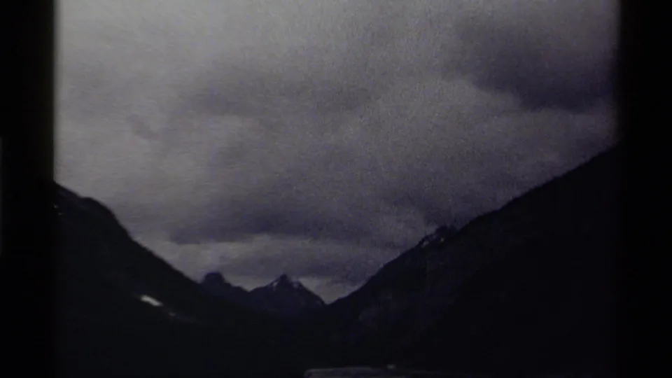 1979 8mm Canada mountain landscape with low cloud cover and a faint pale streak on the dark slope.