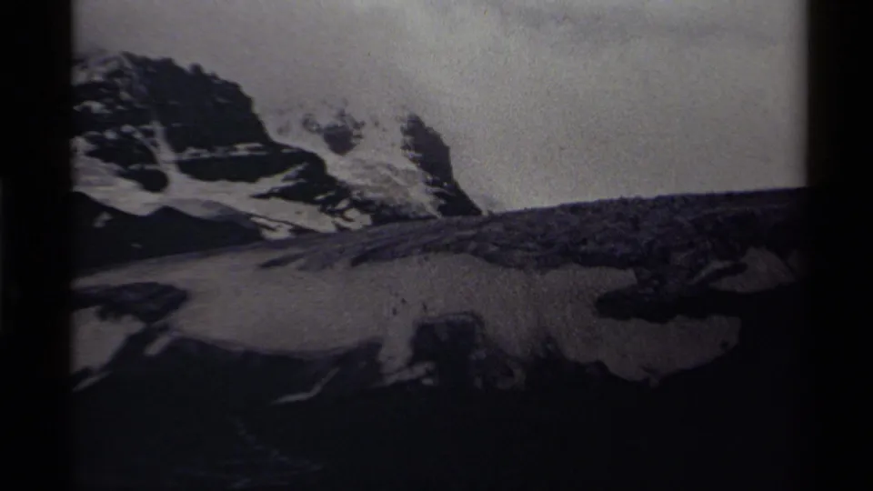 1979 Canadian home-movie frame of rugged snow-covered peaks and dark rock bands in soft black-and-white exposure.