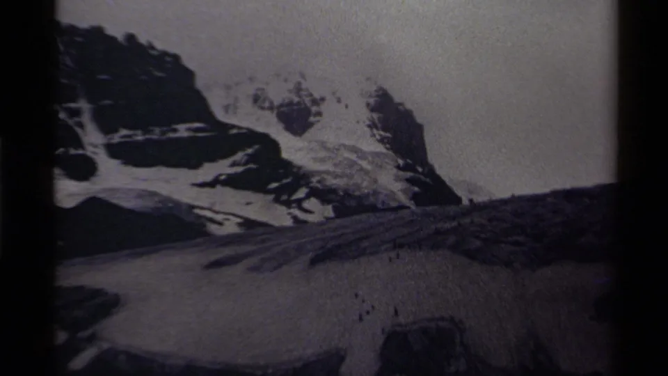 1979 Canadian 8mm still showing snowfields, jagged rock formations, and a muted overcast sky in black and white.