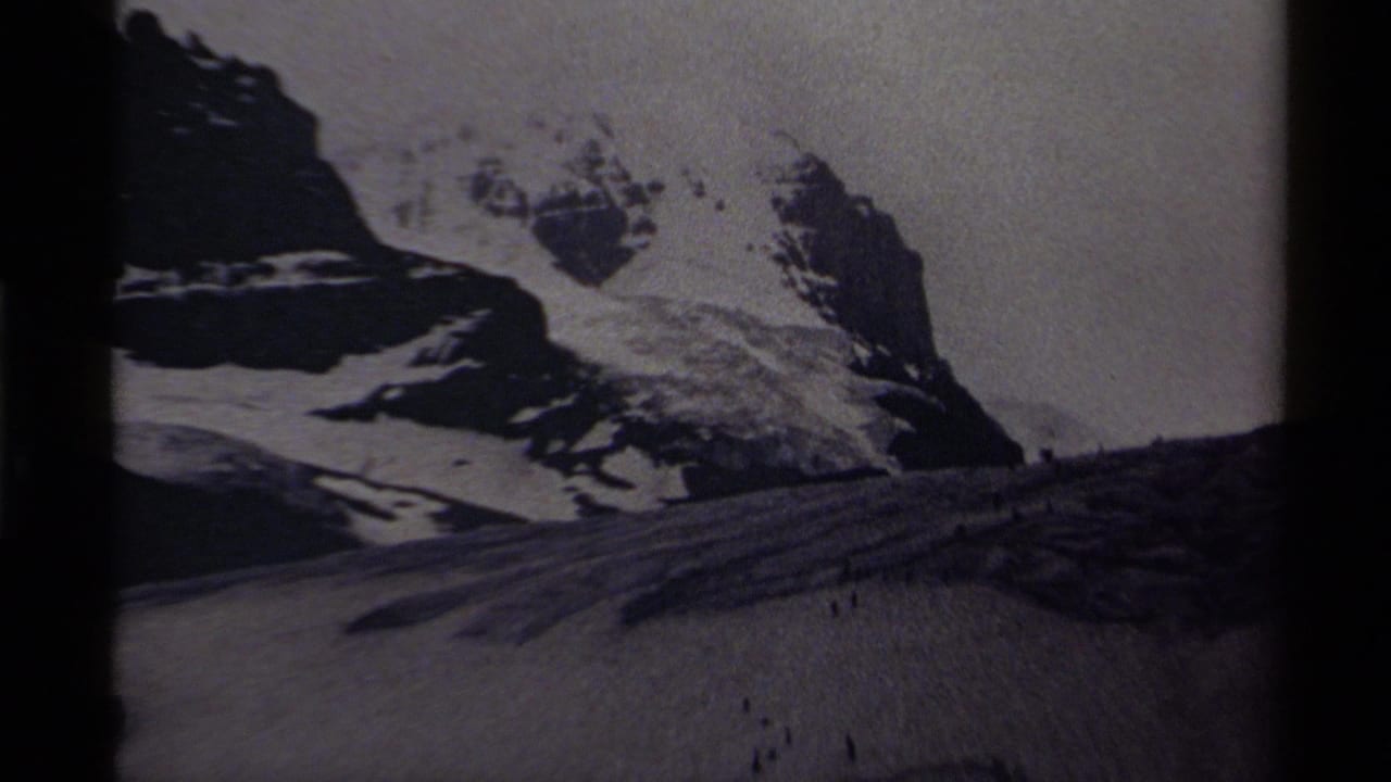 1979 Canada 8mm frame showing snow-covered peaks, dark rock faces, and small people moving across a broad icy foreground.