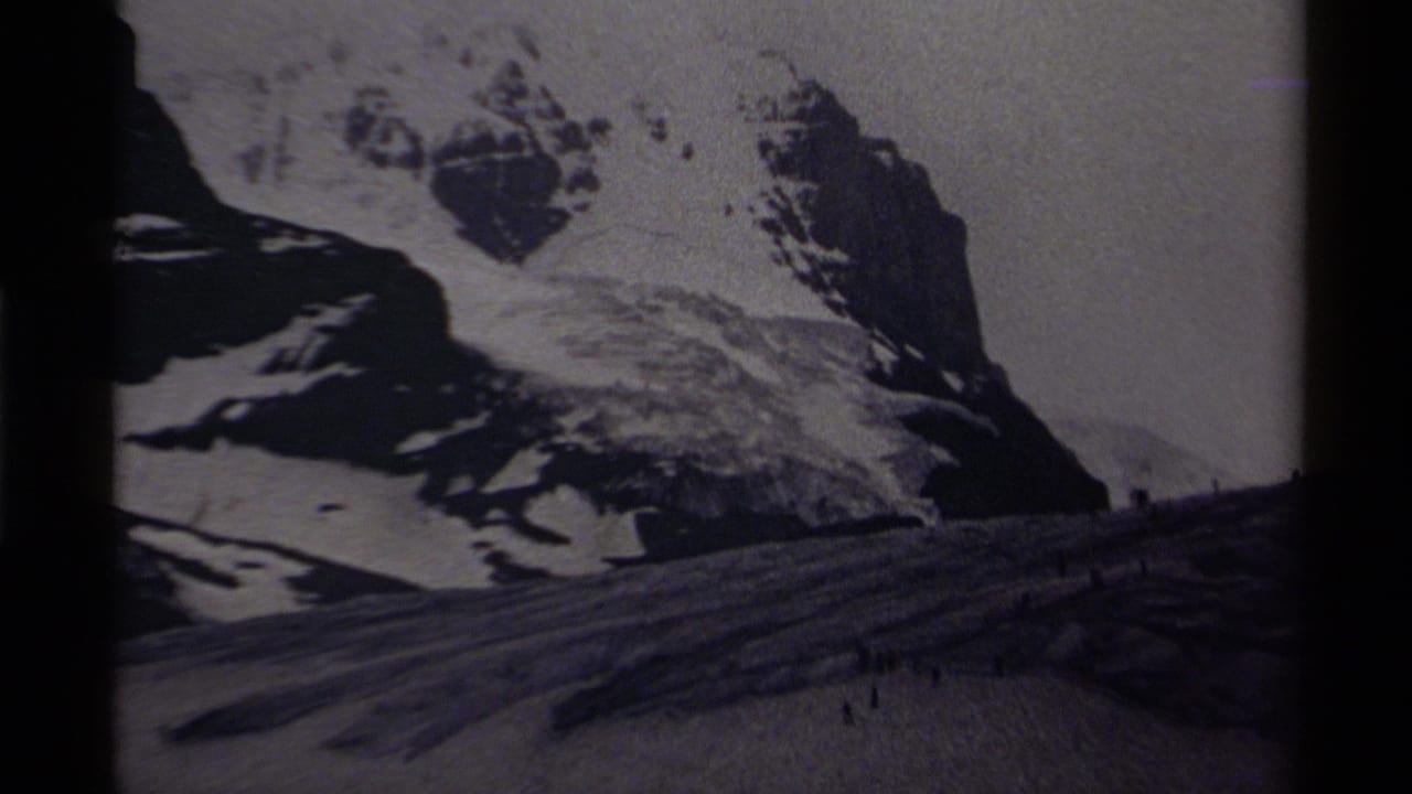 Distant 8mm view of a Canadian alpine snowfield with small figures under rugged, snow-covered peaks.