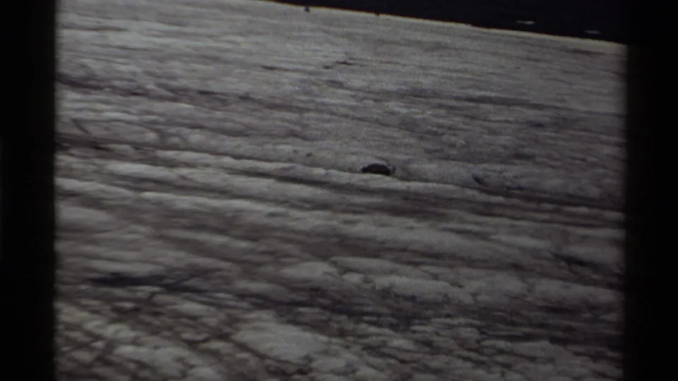 The bear remains small in frame while moving across open rocky terrain in Canada, as supported by the clip metadata.