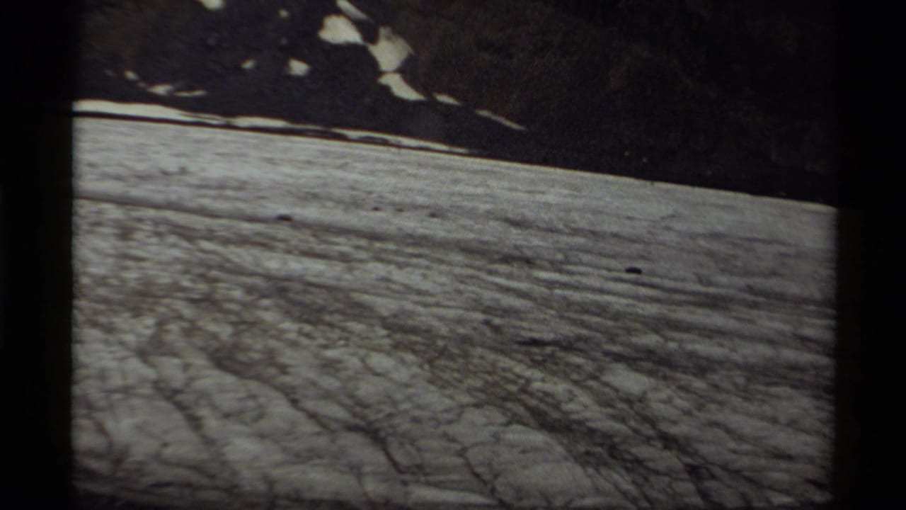 1979 Canada 8mm frame showing a textured snowfield beneath dark, snow-patched mountain slopes.