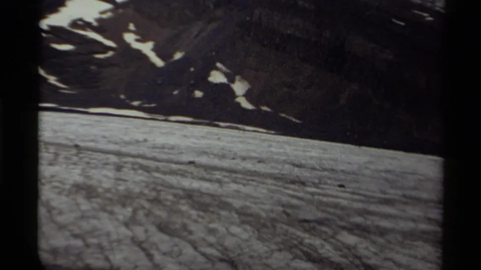 1979 Canadian mountain landscape with a wide snowfield, dark ridgeline, and scattered snow patches in soft 8mm contrast.