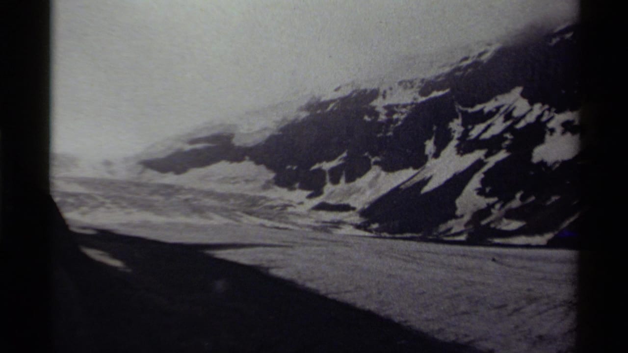 1979 Canadian 8mm frame showing a snowy mountain slope, broad icy terrain, overcast sky, and dark film gate edges.