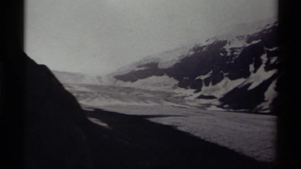 1979 home-movie frame from Canada showing a snow-covered ridge, icy valley floor, and heavy dark edge from the film frame.