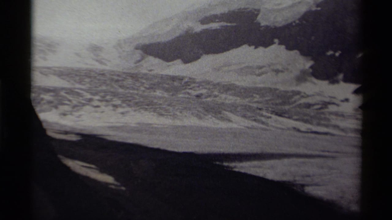 Icy mountain slope and snowfield seen through dark film borders.