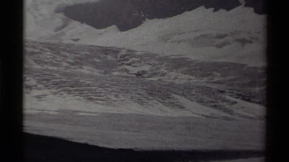 1979 Canada 8mm frame focused on snowy mountain terrain, dark rock bands, and visible grain near the end of the zoom.