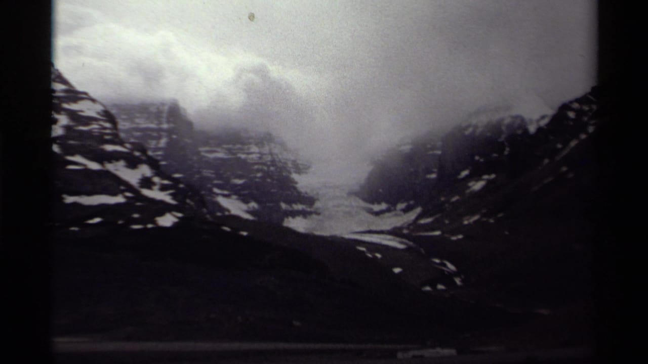 1979 8mm Canada footage showing a glacier descending between dark mountain slopes beneath a cloudy sky.