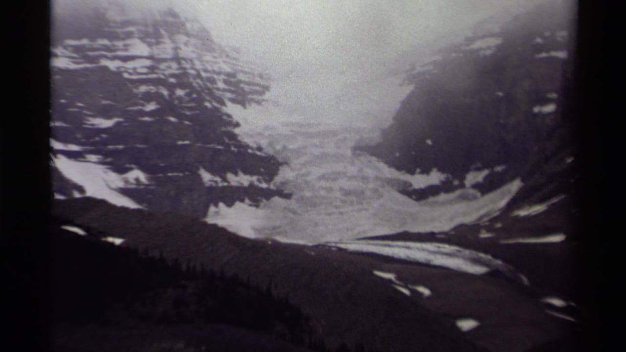 1979 Canadian 8mm view of a glacier and snow patches set between steep, dark mountain slopes.