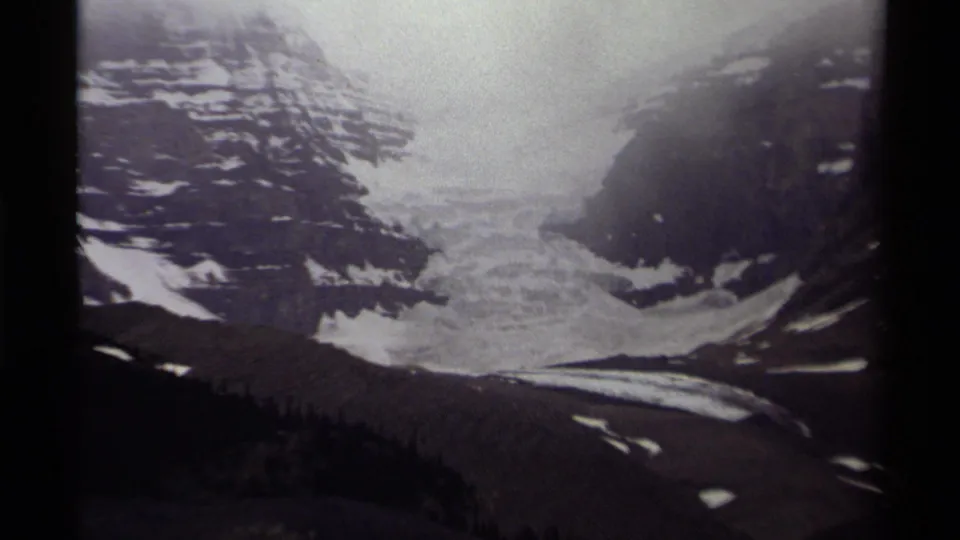 1979 Canadian 8mm view of a glacier and snow patches set between steep, dark mountain slopes.