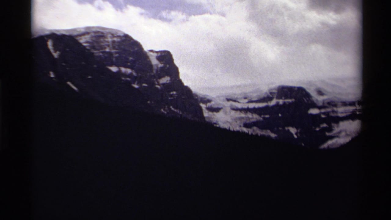 Rocky mountain ridge and dark forest beneath a cloudy sky, seen through film borders.
