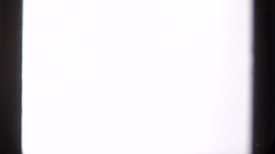 Overexposed 8mm frame from the Canada mountain clip, with a bright field and dark film borders visible at the sides.