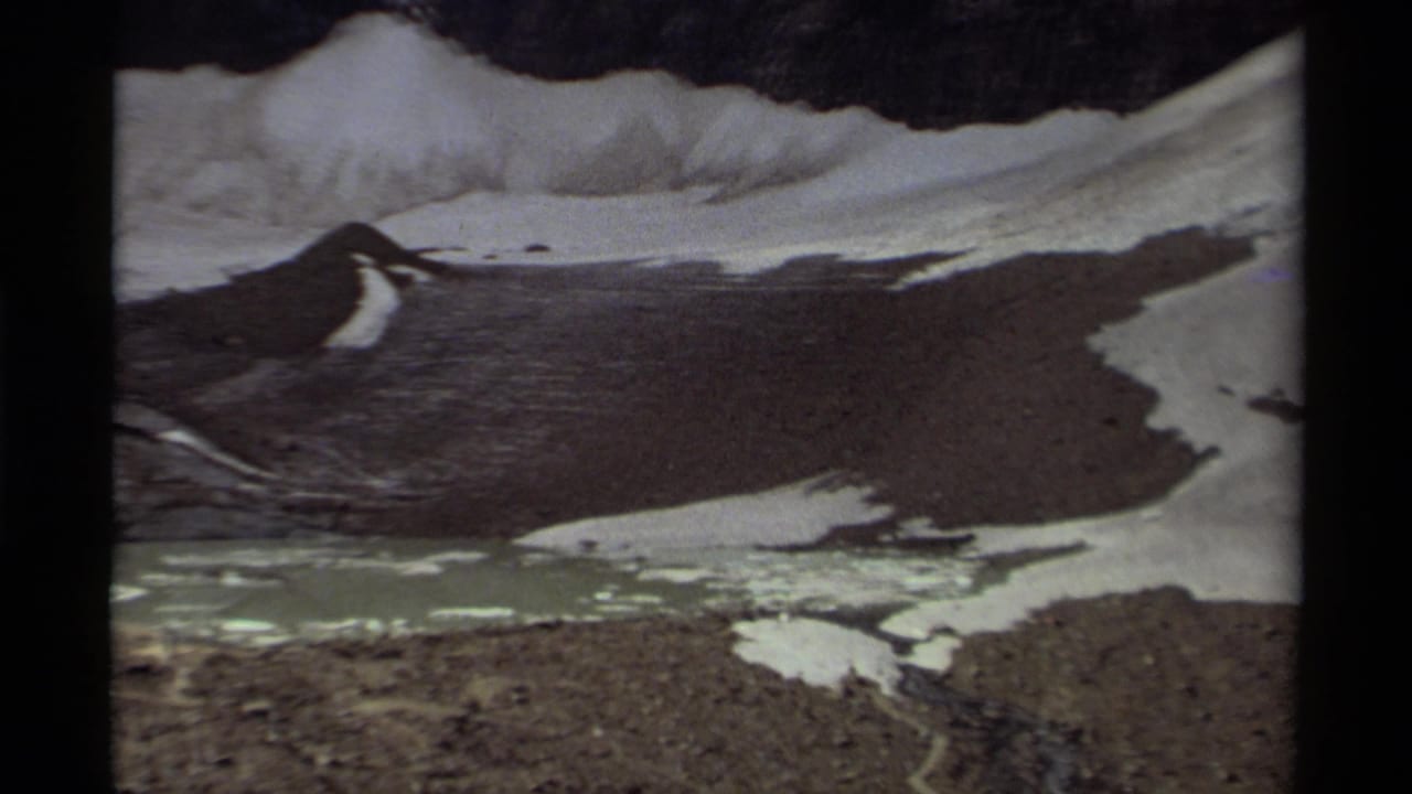 Rocky mountain basin with snow patches above a pale alpine lake.