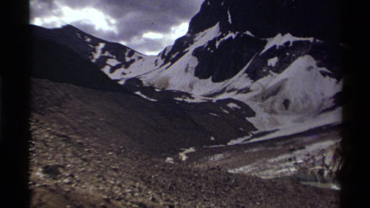 1979 Canadian 8mm view of a rugged snow-covered mountain ridge with dark slopes and bright cloud breaks overhead.