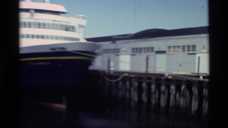 Large white-and-blue passenger vessel appears moored at an Alaska pier in 1977 Super 8 footage.