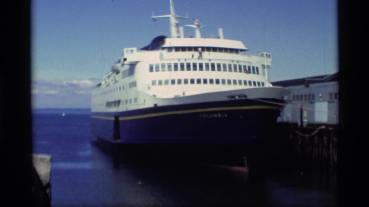 Docked passenger ferry viewed from the front quarter beside a pier.