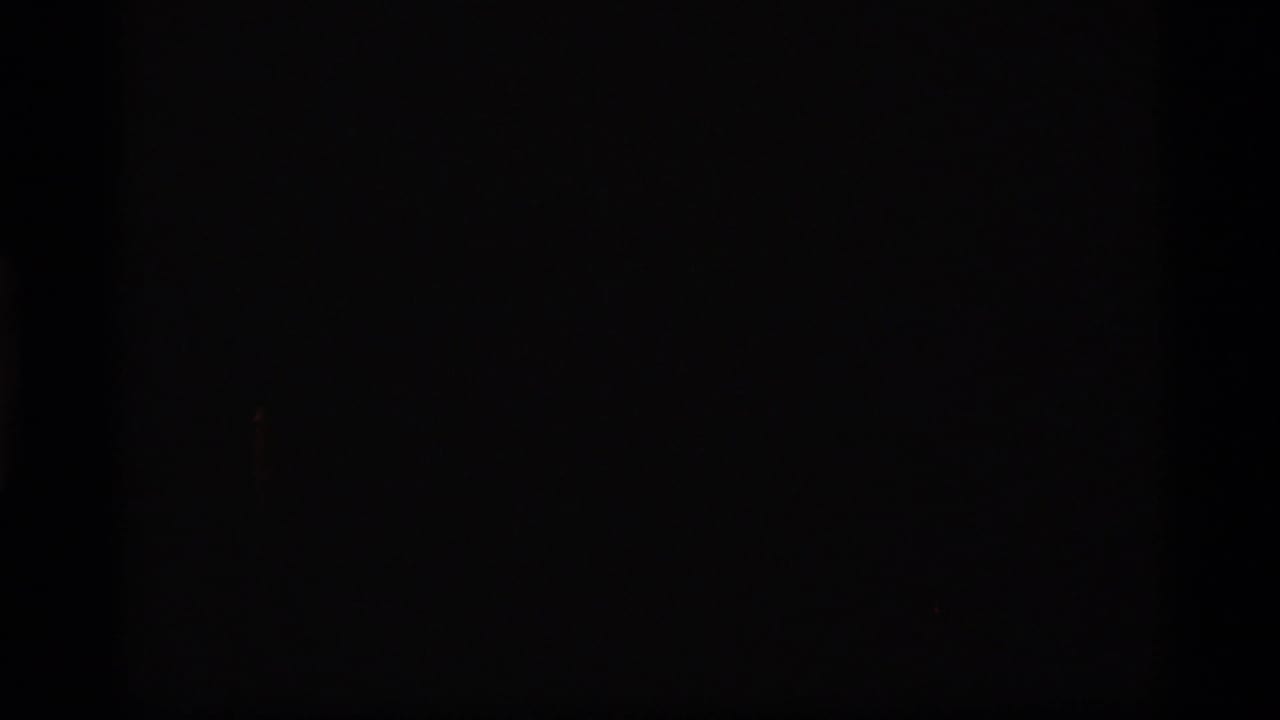 A nearly black 8mm frame, likely leader or underexposed footage at the start of the clip.