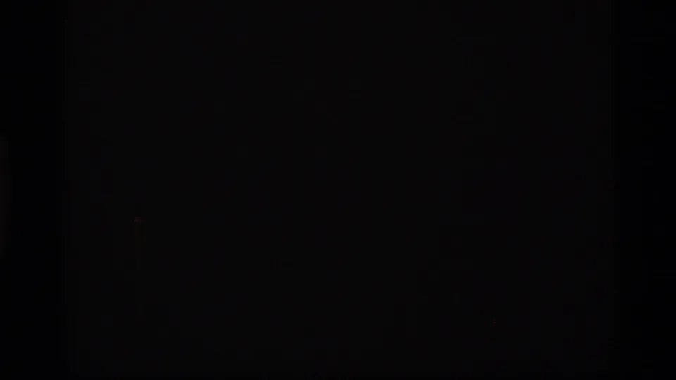 A nearly black 8mm frame, likely leader or underexposed footage at the start of the clip.