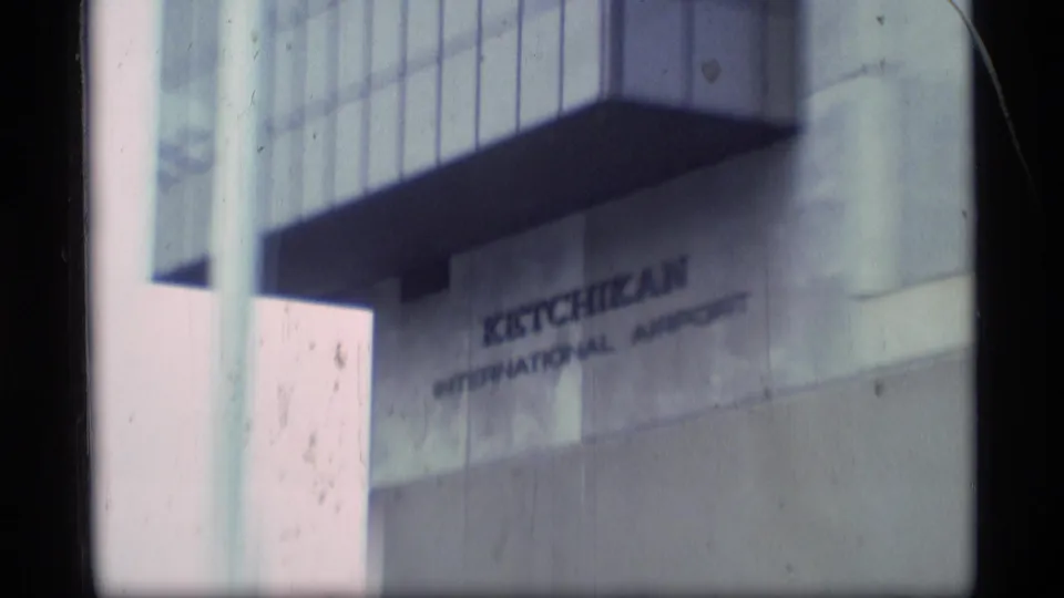 1977 Alaska travel footage showing the exterior sign for Ketchikan International Airport on a terminal wall.