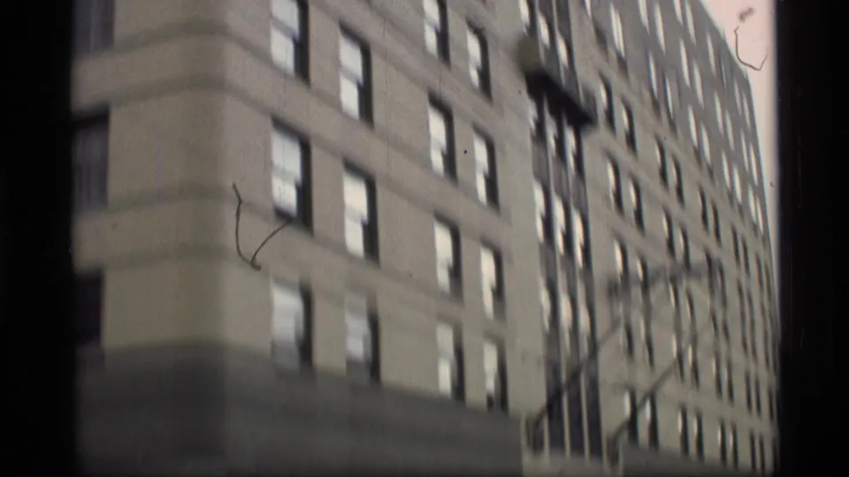 Soft handheld 8mm view of a tall urban building facade in the 1977 Alaska clip.