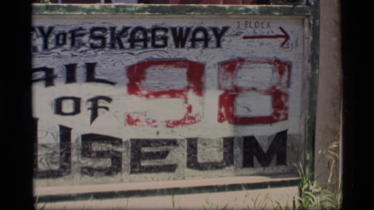 Trail of 98 Museum sign seen closer with red arrow at upper right.
