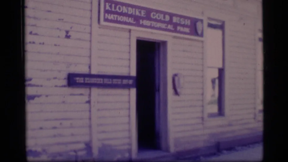 Closer 1977 home-movie view of the Klondike Gold Rush National Historical Park sign above a dark doorway in Skagway.
