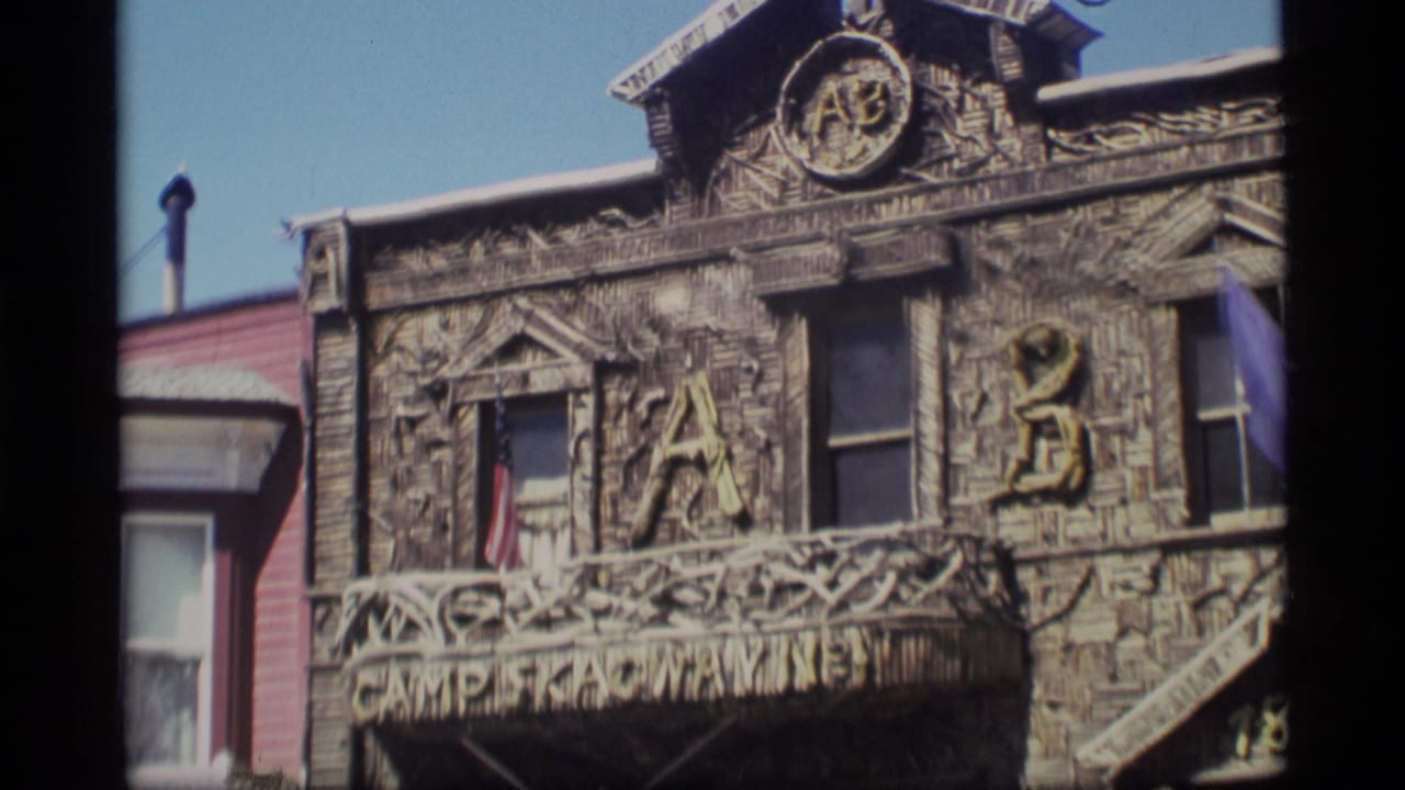 1977 Alaska 8mm frame showing a carved wooden facade with large letters, flags, windows, and CAMP SKAGWAY lettering.