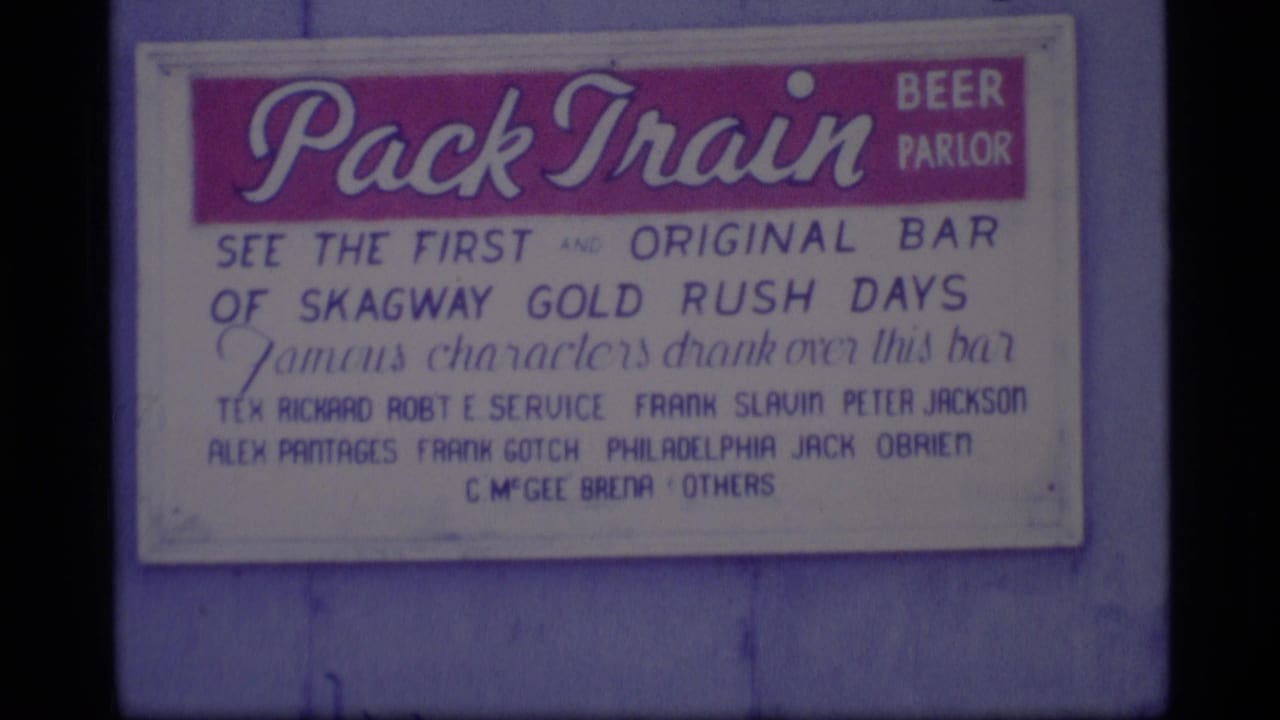 1977 Alaska 8mm frame showing a Pack Train Beer Parlor sign referencing Skagway Gold Rush days.