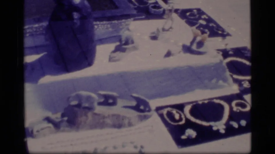 1977 Alaska 8mm frame of jewelry trays and small objects seen through reflective display glass.