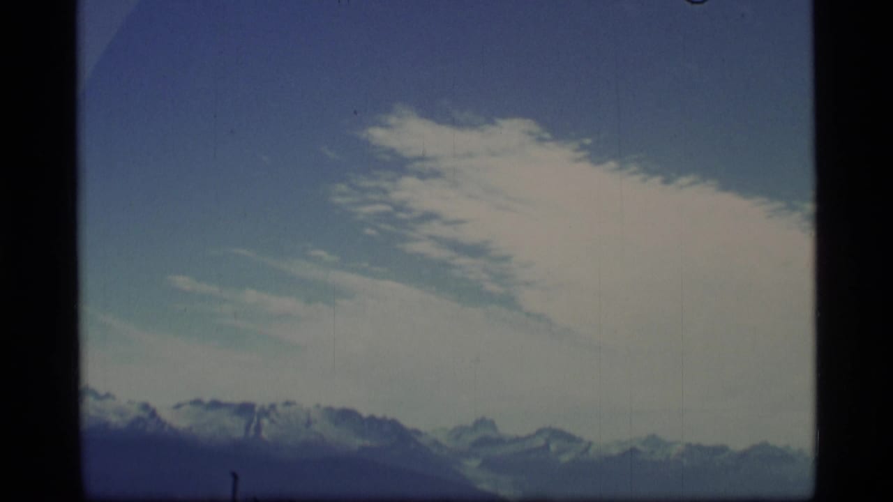 Snowy mountain range beneath blue sky and thin white clouds.