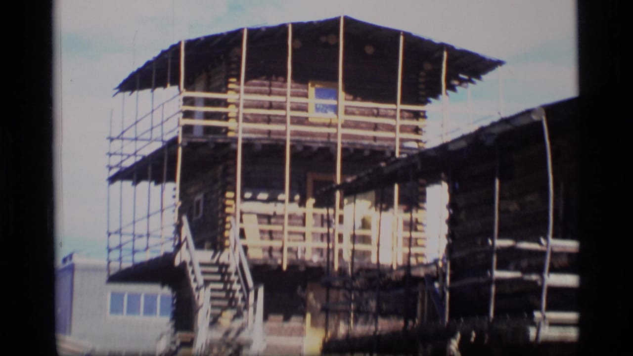 Scaffolded log-style building under construction with exterior stairs.