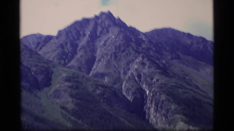 1977 Alaska home-movie view of a jagged mountain peak with shadowed slopes and muted Super 8 color.