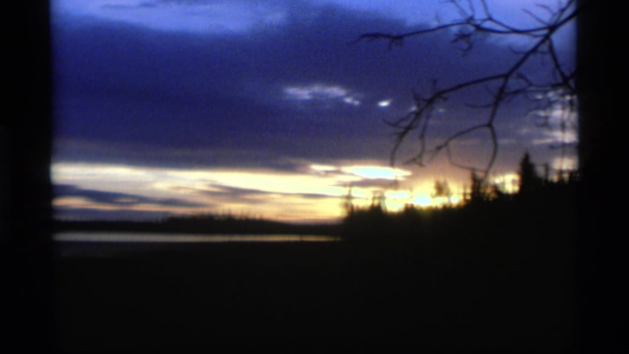 Dark lake and forest silhouettes beneath a blue and gold sunset sky.