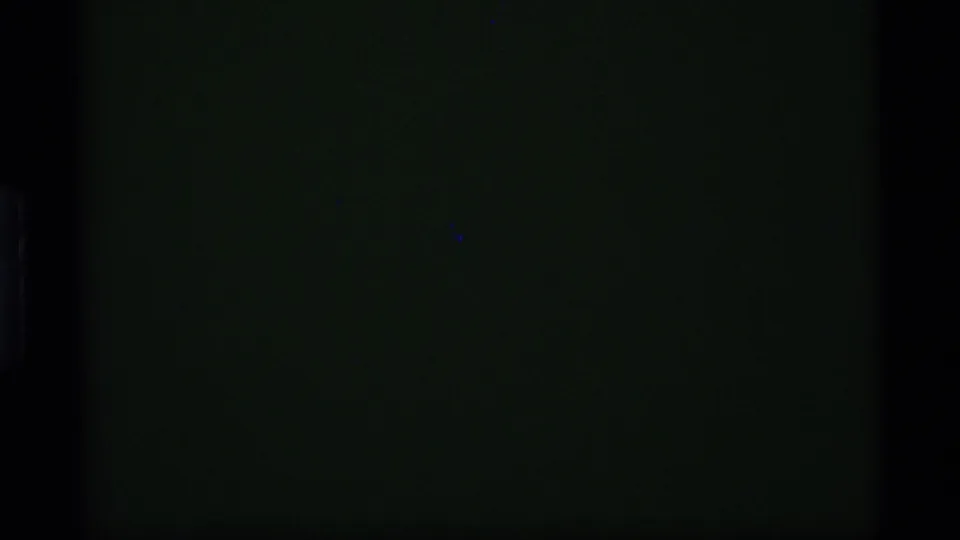 Dark 8mm night frame from the Alaska clip, with only faint green-black exposure and no clearly readable figures in this still.